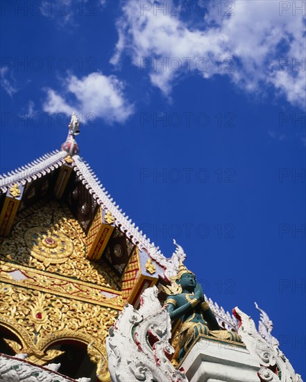 THAILAND, North, Chiang Mai, "Green and gold painted statue of Rama, an incarnation of Vishnu often depicted in temple statuary from the Ramakien National epic.  Point of decorated roof behind."
