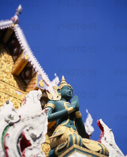 THAILAND, North, Chiang Mai, "Green and gold painted statue of Rama, an incarnation of Vishnu often depicted in temple statuary from the Ramakien National epic.  Point of decorated roof behind."