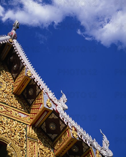 THAILAND, North, Chiang Mai, Detail of highly decorated temple roof with painted carvings of naga water serpents on diagonal.