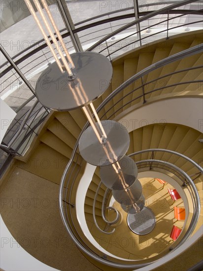 ENGLAND, East Sussex, Bexhill-on-Sea, The De La Warr Pavilion. Interior view down the helix staircase with chrome Bauhaus globe lamps. Three colourful chairs seen at the bottom