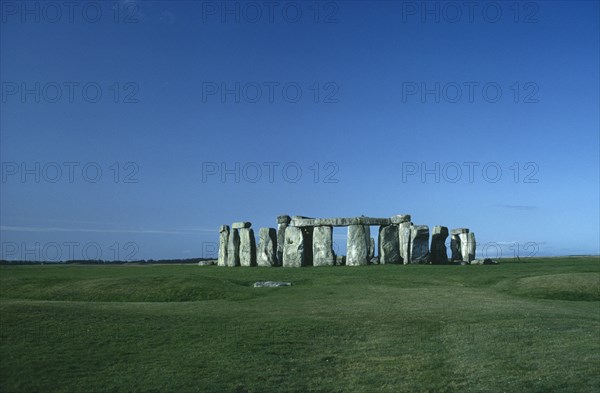 ENGLAND, Wiltshire, Stonehenge, View across the grass on Salisbury Plain towards the standing stones.