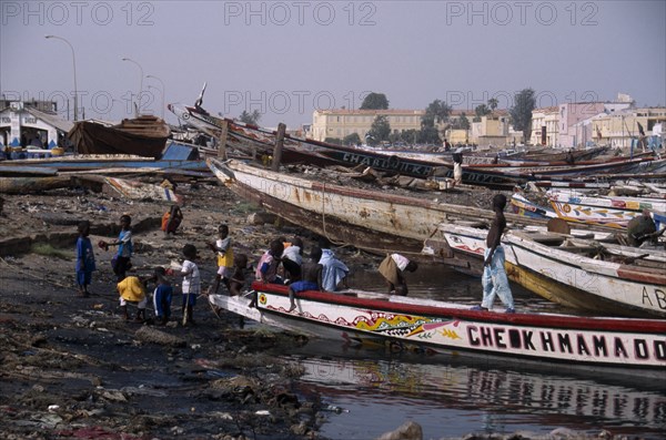 SENEGAL, St Louis, Children playing on shore next to beached boats.