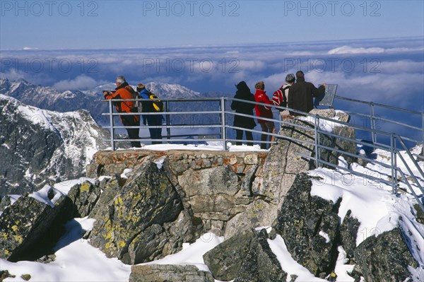 SLOVAKIA, Carpathian Mtns, High Tatras Mtns, People at the Lomnicky Stit viewpoint with views across snowy peaks of the High Tatras mountains and drifting cloud.