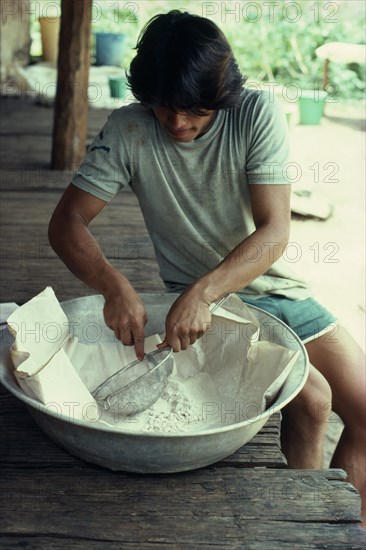 COLOMBIA, Vaupes, William  half-Tukano Indian whose father runs this illegal cocaine lab.  Sieves base cocaine before processing to final product