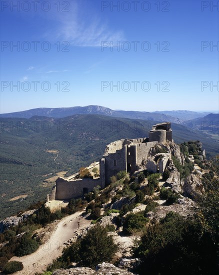 FRANCE, Languedoc-Roussillon, Aude, "Chateau Peyrepertuse.  Ruined medieval Cathar castle stronghold, lower section seen from upper castle.  Fortified walls and turrets along crest of hill. "