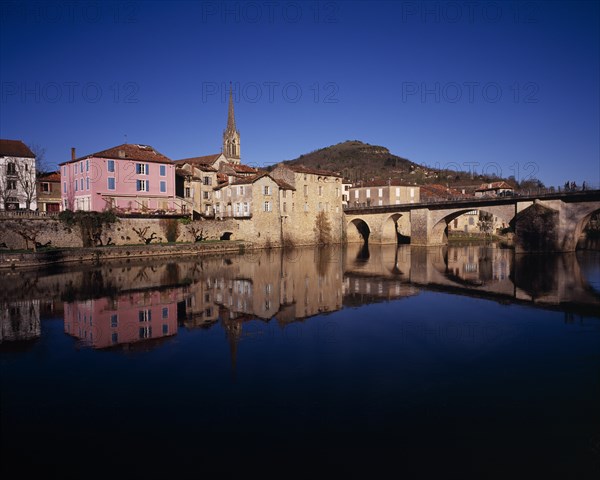 FRANCE, Midi-Pyrenees, Aveyron, "Saint-Antonin-Noble.  Village houses, church spire and bridge reflected in water of the River Aveyron."