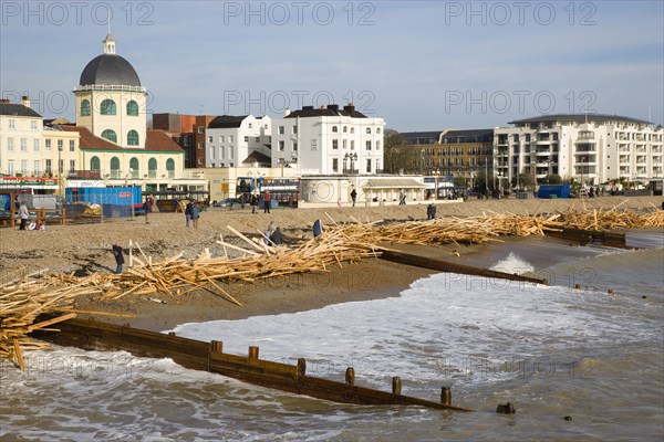 ENGLAND, West Sussex, Worthing, Timber washed up on the beach from the Greek registered Ice Princess which sank off the Dorset coast on 15th January 2008. Wood sits above the high water mark beyond the groynes in front of seafront buildings with people walking past