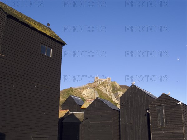ENGLAND, East Sussex, Hastings, Black wooden huts used for storing fishing nets.The East Hill Lift funicular railway behind.