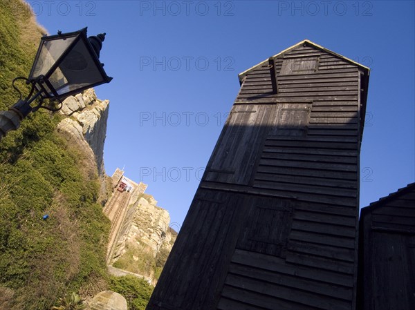 ENGLAND, East Sussex, Hastings, Black wooden huts used for storing fishing nets.The East Hill Lift funicular railway behind.