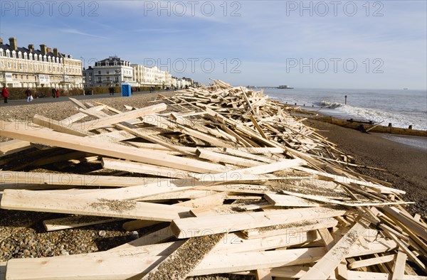 ENGLAND, West Sussex, Worthing, Timber washed up on the beach from the Greek registered Ice Princess which sank off the Dorset coast on 15th January 2008. People walk past on the promenade past seafront buildings with Worthing Pier in the ditance