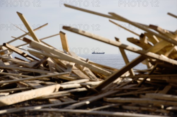 ENGLAND, West Sussex, Worthing, Timber washed up on the beach from the Greek registered Ice Princess which sank off the Dorset coast on 15th January 2008. A cargo ship passes in the distance on the horizon