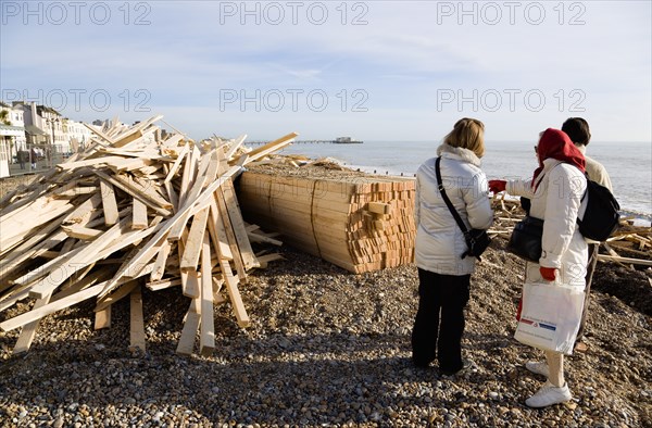 ENGLAND, West Sussex, Worthing, Timber washed up on the beach from the Greek registered Ice Princess which sank off the Dorset coast on 15th January 2008. Three people stand amongst the debris with Worthing Pier in the distance