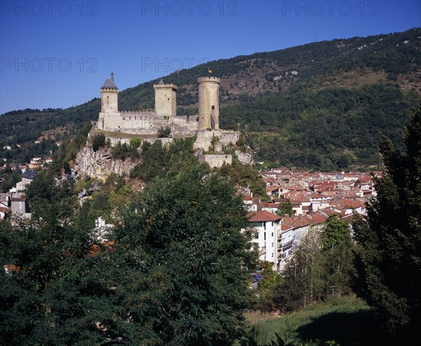 FRANCE, Midi-Pyrenees, Ariege, "Chateau Foix on hilltop above town with tree covered hillside beyond.  Built on 7th C. fortification and known to date from the 10th C., now houses the Musee d’Ariege."