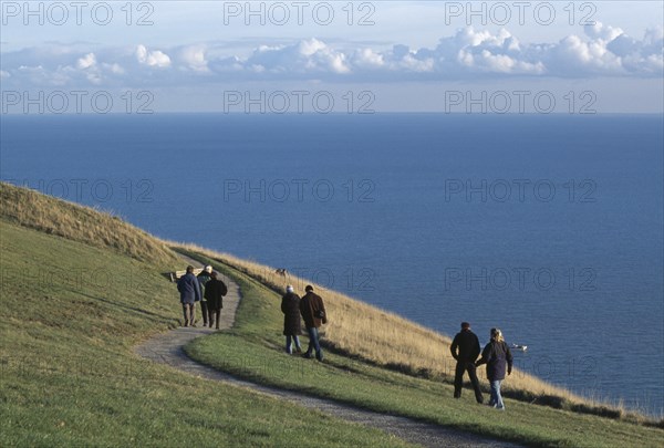 ENGLAND, East Sussex, Eastbourne, People walking together along winding path on cliff walk by Beachy Head