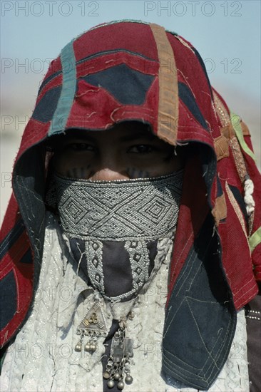 SUDAN, East, People, Head and shoulders portrait of Rasheida nomadic woman wearing embroidered and decorated head covering and veil revealing eyes and facial tattoo.