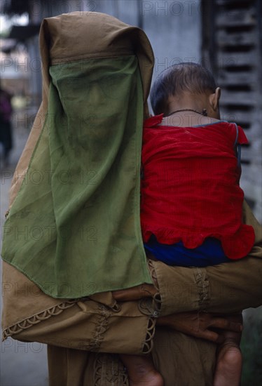 BANGLADESH, Khulna, Char Kukuri Mukuri, Muslim woman wearing full veil and carrying baby against her shoulder.