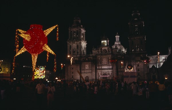 MEXICO, Mexico City, Crowds gathered in the Plaza de la Constitucion or Zocalo at Christmas with illuminated decorations at night.