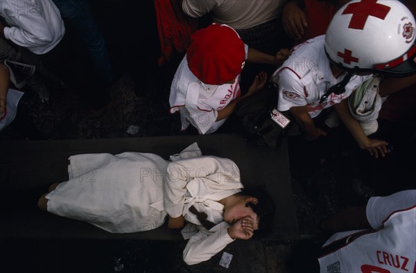 MEXICO, Mexico City, Woman being carried through crowd on stretcher by emergency services during Festival of Our Lady of Guadaloupe