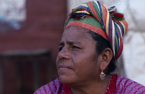 MEXICO, Oaxaca, Juchitan, Head and shoulders portrait of woman wearing coloured headscarf and gold earring.  Three quarters profile left.