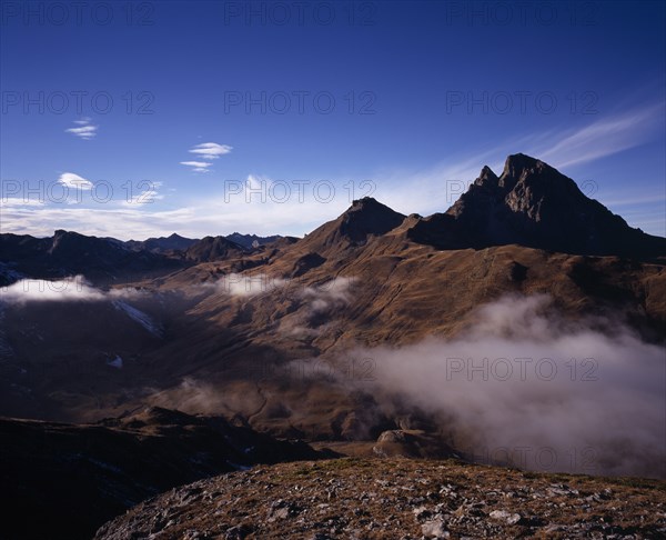 FRANCE, Aquitaine, Pyrenees Atlantiques, Pic du Midi d’Ossau (2884 m) from Col du Pourtalet and mist drifting across valley in foreground.