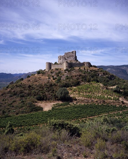 FRANCE, Languedoc-Roussillon, Aude, Chateau de Aguilar.  Ruins of twelth Century Cathar castle set on hillside in the commune of Tuchan.  Inner keep surrounded by outer thirteenth century fortification. Vines growing in valley below.