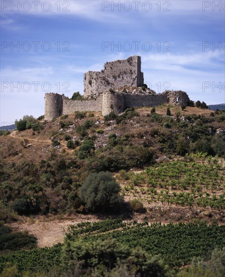 FRANCE, Languedoc-Roussillon, Aude, Chateau de Aguilar.  Ruins of twelth Century Cathar castle set on hillside in the commune of Tuchan.  Inner keep surrounded by outer thirteenth century fortification. Vines growing in valley below.