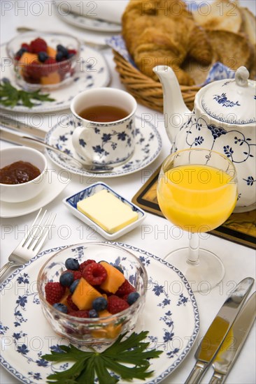 ENGLAND, Food, Meals, "Breakfast table setting with fresh fruit in a bowl, orange juice in a glass, tea in a cup, a teapot, marmalade, butter in a bowl, croissant and toast"
