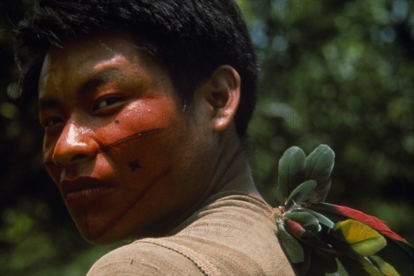 20088952 PERU  Rio Pachitea Portrait of young Campa tribesman with red and black painted face looking towards camera over his shoulder.