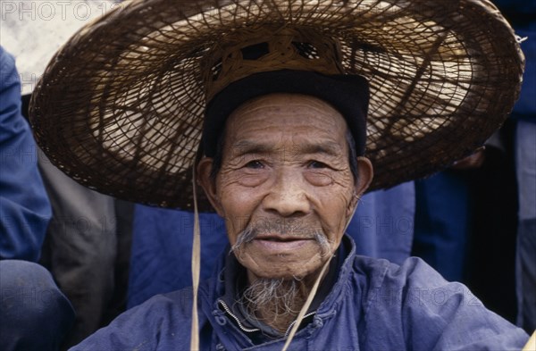 20088801 CHINA Guizhou Province Anshun District Head and shoulders portrait of elderly Bouyei man wearing wide brimmed woven hat.