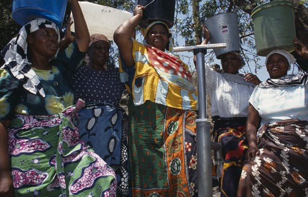 20088822 TANZANIA  Shinyanga Women at standpipe carrying pails of clean water on their heads.  Following 1994 cholera outbreak an urban health programme was set up to teach health awareness.