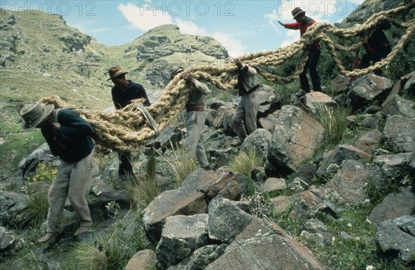 20088962 PERU  Apurimac Gorge Men from the Chumbivilcas hills carrying length of thick rope made from woven bunch grass to make cable or trense used for bridge construction by local villagers.