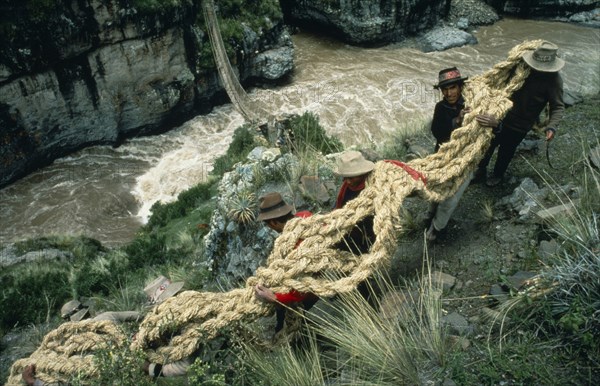 20088963 PERU  Apurimac Gorge Men from the Chumbivilcas hills carrying length of thick rope made from woven bunch grass to make main cable or trense used for bridge construction by local villagers.