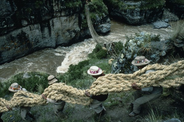 20088964 PERU  Apurimac Gorge Men from the Chumbivilcas hills carrying length of thick rope made from woven grass to make main cable or trense used for bridge construction by local villagers