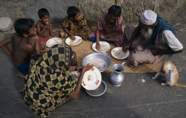BANGLADESH, Khulna, Char Kukuri Mukuri, "Family having breakfast of rice, seated on mat laid on ground and eating with their right hands."