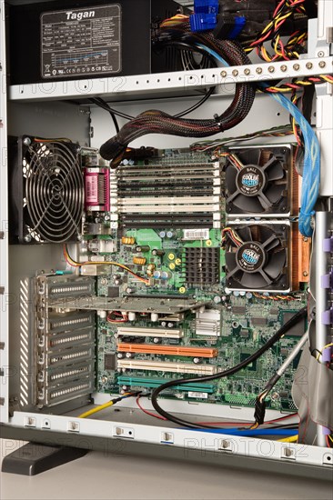 INDUSTRY, Machinery, Computers, "Desktop PC personal computer with the side panel off showing the power unit, case extractor fans, double processors with fans, motherboard, cables, RAM memory cards and slots, and PCI network card with spare slots"