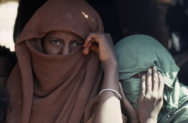 20088677 SUDAN Red Sea Hills Province People Head and shoulders portrait of two Beja nomad Arab girls  veiled so that only their eyes are visible.