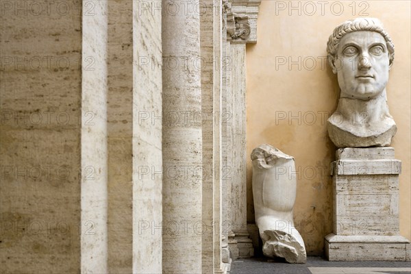 ITALY, Lazio, Rome, Capitoline Museum at Palazzo dei Conservatore with the head and arm of the colossal marble statue of the Roman Emperor Constantine the First beside Ionic columns