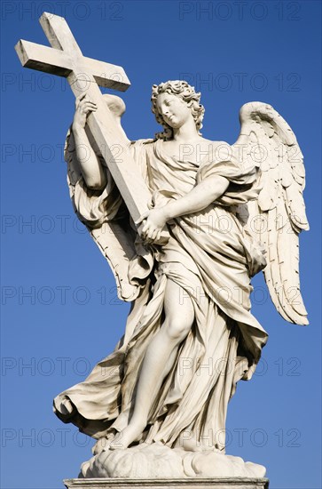ITALY, Lazio, Rome, White marble statue of a winged female angel holding a cross on the Ponte Sant Angelo bridge with a clear blue sky