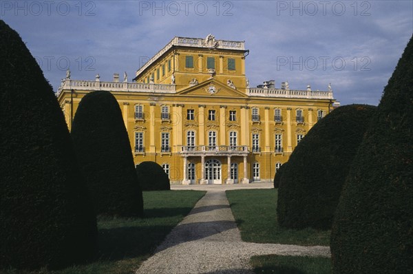 HUNGARY, Burgenland, Eisenstadt , Esterhazy Palace yellow painted exterior seen from formal gardens with mature hedging