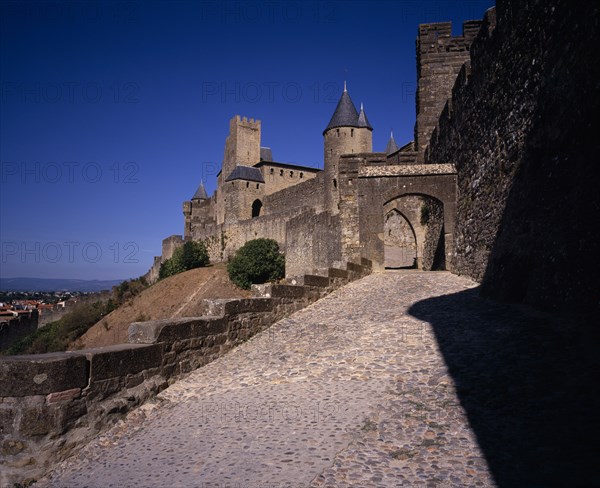 FRANCE, Languedoc-Roussillon, Aude, Carcassonne.  Gateway in medieval fortified outer walls of town with the Counts Chateau behind.