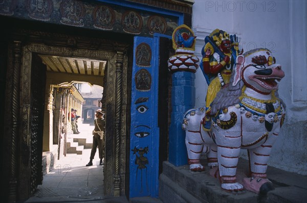 NEPAL, Kathmandu, Dubar Square. Royal Palace or Hanuman Dhoka. Statue of Shakti riding a lion next to private entrance to palace with a guard seen through doorway