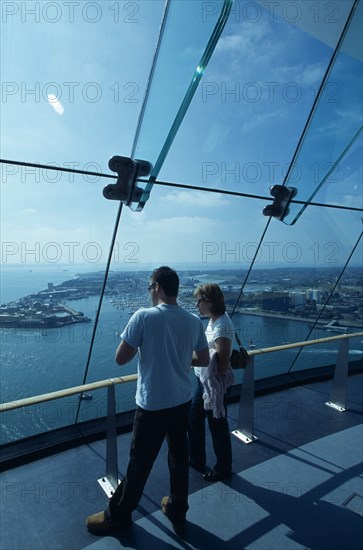 ENGLAND, Hampshire, Portsmouth, "Gunwharf Quays. The Spinnaker Tower. Interior at top of tower on the observation deck with a man and woman looking out of glass windows providing a 320° view of the city of Portsmouth, the Langstone and Portsmouth harbours, and a viewing distance of 37 kilometres (23 miles"