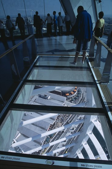 ENGLAND, Hampshire, Portsmouth, "Gunwharf Quays. The Spinnaker Tower. Interior at top of tower with a glass floor window  looking down. Visitors looking out glass windows on the observation deck providing a 320° view of the city of Portsmouth, the Langstone and Portsmouth harbours."