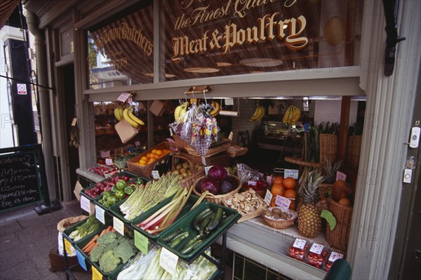 ENGLAND, East Sussex, Hastings, Old Town Butchers on George Street.  Shop frontage with fruit and vegetables displayed on stall outside with a meat and poultry sign on window.