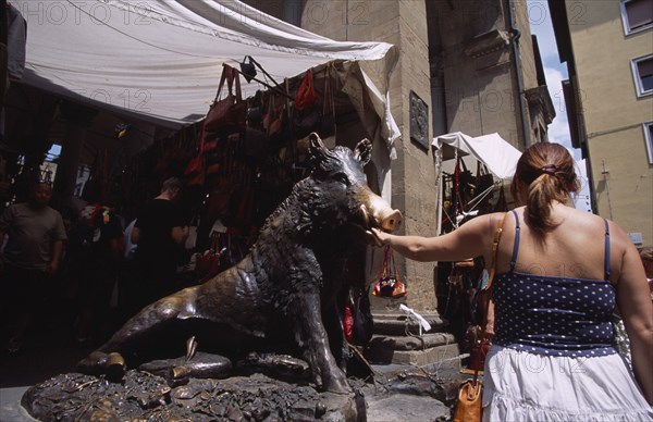 ITALY, Tuscany, Florence, Mercato Nuovo. Fontana del Porcellino. Bronze fountain of a boar with a woman rubbing the snout for good luck