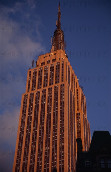 USA, New York, New York City, "Part view of the Empire State Building from 7th Avenue / West 31st Street.  Art Deco, steel framed building with radio and TV mast completed in 1931. Deep orange light.   Designed by architect William Lamb of Shreve, Lamb and Harmon Associates."