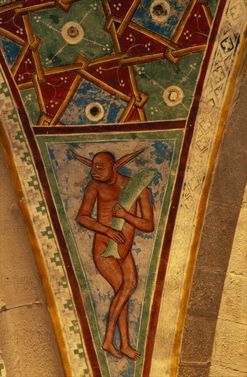 ITALY, Lombardy, Lake Maggiore, Angera.  Architectural detail and painting in Rocca di Angera medieval castle depicting figure carrying fish and abstract pattern set in space between arches or spandrel