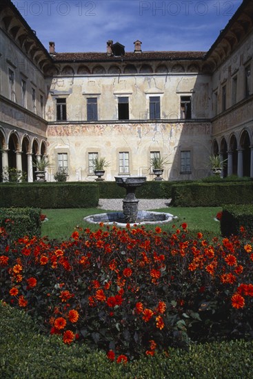 ITALY, Lombardy, Bisuschio, Villa Cicogna Mozzoni east of Lake Maggiore.  Exterior of Renaissance villa built between 1400 -1500 by the Mozzoni family.  Water feature and dahlias in foreground.