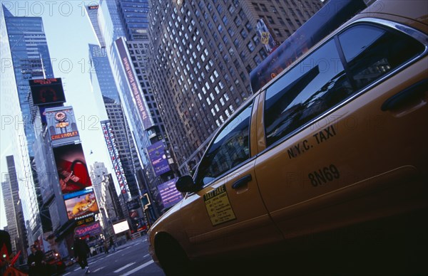 USA, New York, New York City, Times Square.  Yellow taxi cab on street with skyscraper buildings and illuminated advertising.