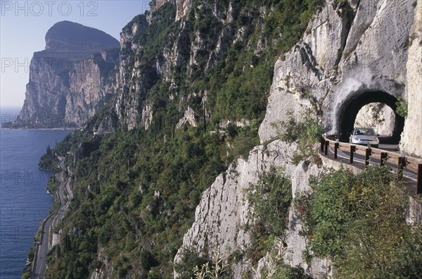ITALY, Lombardy, Lake Garda Area, Car on high Gardesana Occidentale road with tunnels through cliff beside Lake Garda near Limone.
